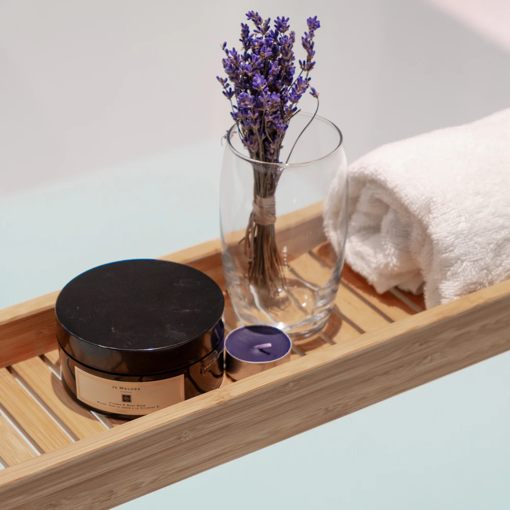 Charola de madera con flores secas, crema y una toalla doblada